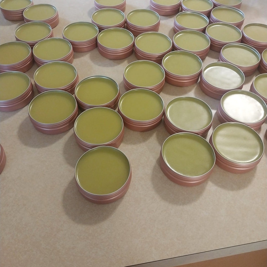 A full batch of Melzayta Body Balm in rose-gold tins