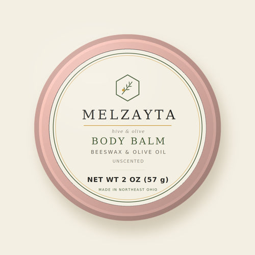 Melzayta Body Balm: closed rose-gold tin with the cream Body Balm label, beeswax and olive oil, 2 oz